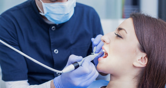 A dentist is seen doing a cleaning on a patient